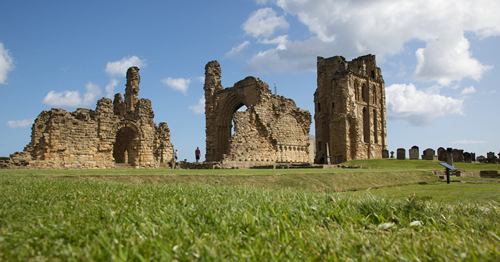 View of people exploring the ruins of Tynemouth Priory on a bright sunny day.